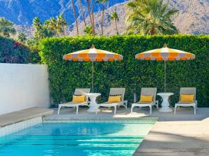 a group of chairs and umbrellas next to a pool at Villa Caliente in Palm Springs
