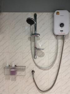 a shower with a hose attached to a tile wall at Stay at 115 in Hat Yai