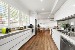 una cucina con pareti bianche e pavimenti e finestre in legno di Boutique Living East Toowoomba a Toowoomba