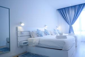 a white bedroom with a large white bed and a mirror at Tung Kidcove Centrum Cameron in Brinchang