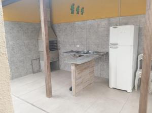 a small kitchen with a refrigerator and a sink at Cantinho da Quinta 2 Quartos in Barra Velha