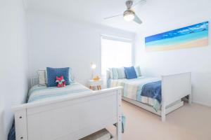 a white bedroom with two beds and a painting at 8 Ocean Avenue - Pet Friendly, Wi-Fi, views and Aircon in Anna Bay