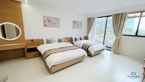 a bedroom with two beds and a mirror at The Healing Luxury Hotel in Buon Ma Thuot