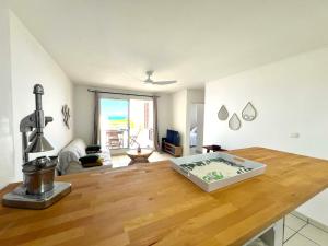 a living room with a wooden table with a large appliance at Le Blue Ocean - vue mer - parking - clim - wifi in Saint-Gilles-les-Bains +10 photos
