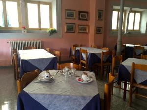 a dining room with tables with blue and white tablecloths at Albergo Ape Elbana in Portoferraio