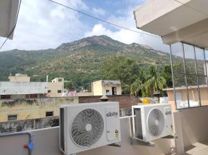two air conditioners on a balcony with a mountain at Aalaya Darshan Homestay in Tiruvannāmalai