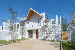 une grande maison blanche avec une allée dans l'établissement New Elegance & Tropical Luxury - 4BR Pool Villa in Lux Pride 2 V8 Residence, near Laguna, à Ban Pak Lak
