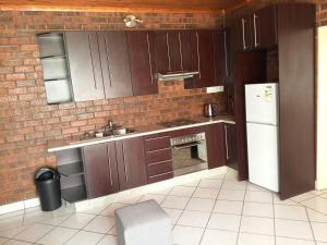 a kitchen with wooden cabinets and a brick wall at Ubuntu Heaven in Germiston