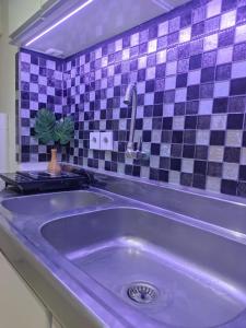 ein lila Waschbecken im Badezimmer mit lila Fliesen in der Unterkunft Pakuwon Mall Orchard Tanglin Anderson Tower WIFI Netflix by AquHome in Surabaya