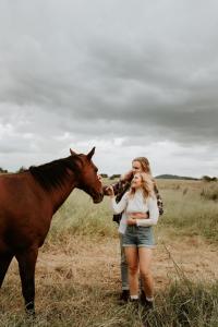 a woman standing next to a brown horse at The Forager Glamping at Twigley Farm in Marburg