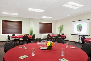 una sala de conferencias con mesas y sillas rojas y una pantalla en Super 8 by Wyndham Red Lake ON en Red Lake