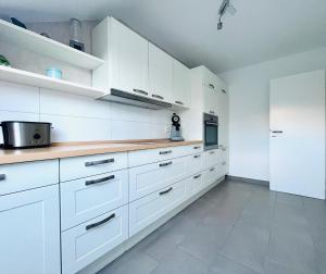 a white kitchen with white cabinets and white appliances at 75 qm Ferienwohnung Am Niederrhein mit privater Sauna in Friedrichsfeld