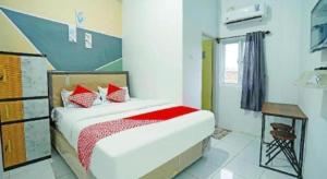 a bedroom with a bed with red pillows at OYO 91559 Kost Bangau Syariah in Prabumulih