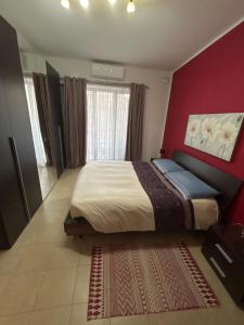 une chambre avec un grand lit avec un mur rouge dans l'établissement Swieqi sunny central airy quiet Apartment in Malta, à Is-Swieqi 20 autres photos