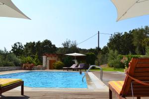 a swimming pool with two chairs and an umbrella at Alkyon Villas in Syvota