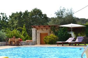 a swimming pool with two chairs and an umbrella at Alkyon Villas in Syvota