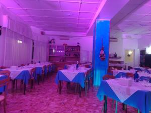 a dining room with white tables and purple lighting at Hotel San Paolo in Varazze