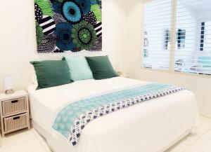 un lit blanc dans une chambre blanche avec une fenêtre dans l'établissement Reef Luxury Apartment, à Port Douglas 18 autres photos
