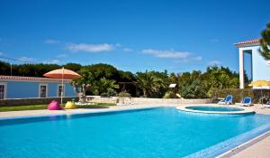 a swimming pool with two chairs and a house at Hotel Neptuno in Peniche