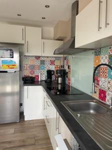a kitchen with white cabinets and a stainless steel sink at L Envie d Opale Maison familiale avec jardin a Wimereux in Wimereux