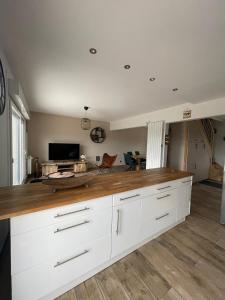 a large kitchen with white cabinets and wooden counter top at L Envie d Opale Maison familiale avec jardin a Wimereux in Wimereux +6 photos