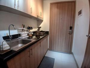 a kitchen with a sink and a wooden door at Shore2 Haven - Chic Condotel Near Mall of Asia in Manila