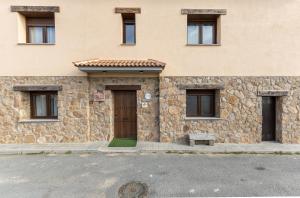ein Steingebäude mit einer Tür und einer Bank davor in der Unterkunft Casa Rural Camino De Avila in Mediana de Voltoya