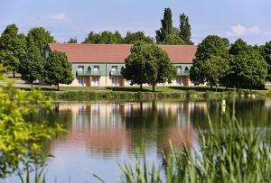 a building sitting next to a lake with trees at ibis Styles Bourbon Lancy in Bourbon-Lancy
