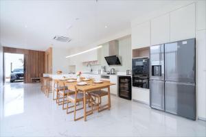 une grande cuisine avec une table et des appareils en bois dans l'établissement New Elegance & Tropical Luxury - 4BR Pool Villa in Lux Pride 2 V8 Residence, near Laguna, à Ban Pak Lak