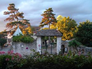 a stone building with a gate and trees at Logis Hôtel-Restaurant Le Val d'Amby in Hières-sur-Amby