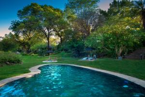 a swimming pool in a yard with trees at Ursula's Homestead in Victoria Falls