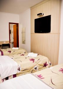 a room with two beds and a flat screen tv at Hotel Castro Mendes in Campinas