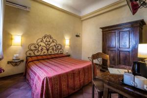 フィレンツェにあるホテル　マリオズのベッドルーム1室(ベッド1台付)、木製キャビネットが備わります。