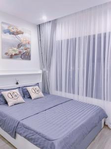 a bedroom with a bed with blue sheets and a window at Y Vi Vinhomes Grand Park in Long Bình