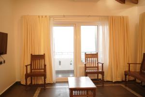 un salon avec deux chaises et une table et une fenêtre dans l'établissement Golden Sands Cherai, à Cherai Beach
