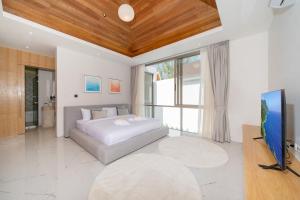 a bedroom with a bed and a flat screen tv at Your Private Piece of Paradise! 4BR Pool Villa in the New Lux Pride 2 V9 Residence in Ban Pak Lak