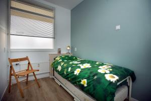 ein Schlafzimmer mit einem Bett mit einer grünen Decke mit Blumen in der Unterkunft bij Miep in Egmond aan Zee