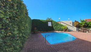 a small swimming pool in front of a hedge at Corona Del Mar 23 in Uvongo Beach