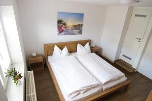 a bedroom with a bed with white sheets and pillows at Haus Rena am Südstrand in Borkum