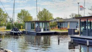 a couple of houses on a dock on a body of water at Houseboat Heeg 4 persons in Heeg