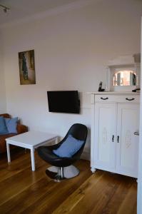 a room with a chair and a table and a tv at Villa Scherz - stilvoll, zentral, ruhig, EG in Borkum
