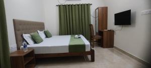 a bedroom with a bed with green curtains and a television at Zora Rooms in Alleppey +10 photos