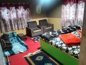 a room with two beds and chairs and curtains at New Buddha Homestay By StayApart in Tabo