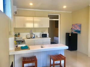 uma cozinha com armários brancos e uma geladeira preta em Kidsfirst Apartment 1 - Duncan Road Suva em Suva