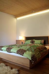 a bedroom with a bed with a green comforter and pillows at Apartment Urstöger in Gosau