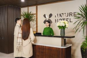 a man and a woman standing at a reception desk at Nature Hotel - Win Happy in Da Lat