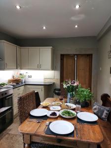 a kitchen with a wooden table with plates on it at The West Wing in Whitford