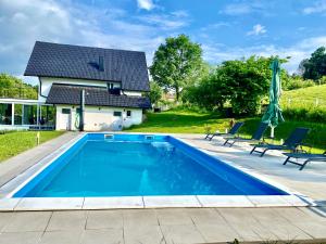 a swimming pool with two chairs and a house at Relax House in Banja Luka
