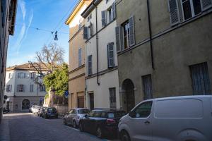 a street with cars parked on the side of a building at Parma, Antico Studio dietro al Battistero in Parma
