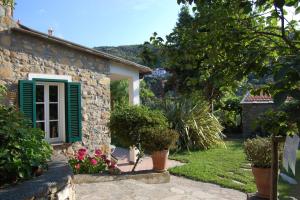 a stone house with a green window and plants at Casa Didun -apart Bartume' in Dolcedo